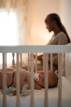 Newborn sleeping while mother working on background