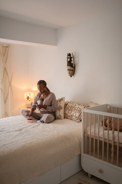 Focused mother using breast pump in bed