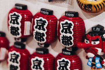 Traditional Japanese tourist souvenirs and gifts from Kyoto, Kansai, Japan, with daruma figures, kitsune fox, tengu mask, fridge magnets, toys figurines, key ring keychain, in a local vendor gift shop