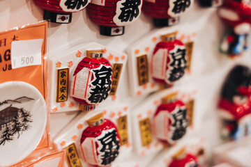 Traditional Japanese tourist souvenirs and gifts from Kyoto, Kansai, Japan, with daruma figures, kitsune fox, tengu mask, fridge magnets, toys figurines, key ring keychain, in a local vendor gift shop