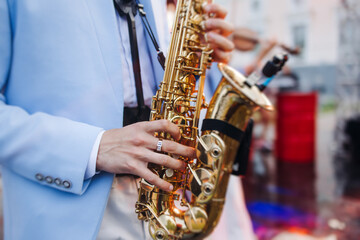 Naklejka premium Concert view of saxophonist musician, saxophone sax player with vocalist and musical band during jazz orchestra show performing music on a stage in the scene lights, concert in a musical club hall