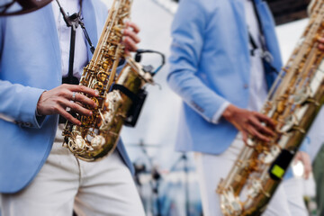 Obraz premium Concert view of saxophonist musician, saxophone sax player with vocalist and musical band during jazz orchestra show performing music on a stage in the scene lights, concert in a musical club hall