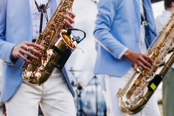 Obraz premium Concert view of saxophonist musician, saxophone sax player with vocalist and musical band during jazz orchestra show performing music on a stage in the scene lights, concert in a musical club hall