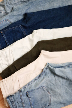 A row of folded trousers and jeans in various shades