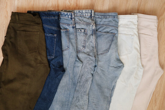 A row of folded trousers and jeans in various shades