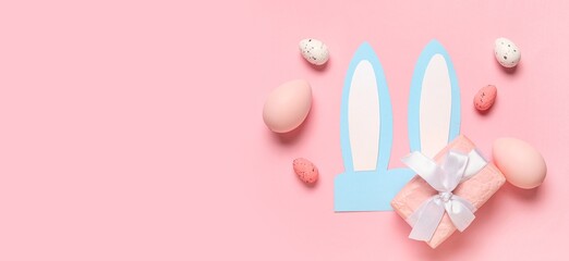 Paper bunny ears, Easter eggs and gift on pink background with space for text, top view