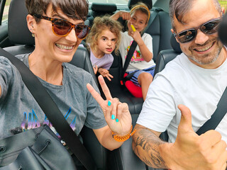 Family taking selfie while enjoying road trip in car