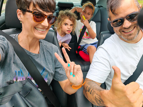 Family taking selfie while enjoying road trip in car