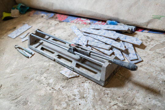 Manual tile cutter lying on dusty floor with ceramic tiles in Senegal