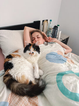 UGC photo of blonde woman sleeping alongside her calico cat 