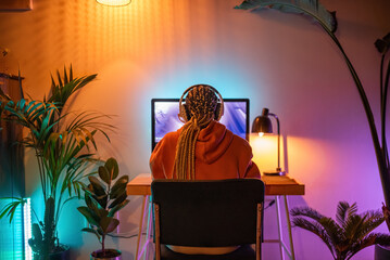 Woman playing video games on computer at cozy room