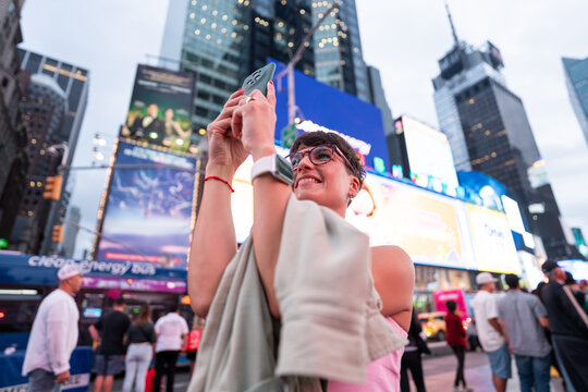 Young woman taking photos in Times Square, New York City