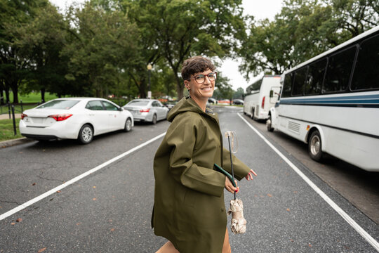 Smiling woman walking in Washington D. C. With folded umbrella