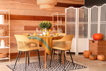 Autumn table setting with flowers and pumpkins in dining room