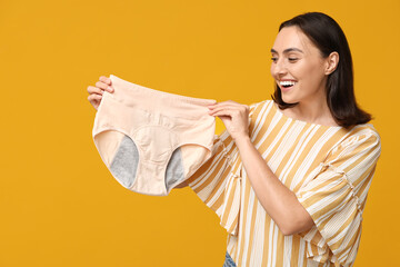 Beautiful young woman with period panties on yellow background