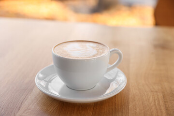 Cup of aromatic coffee on wooden table in cafe, closeup
