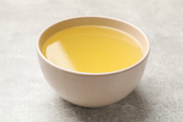 Tasty chicken bouillon in bowl on grey table, closeup
