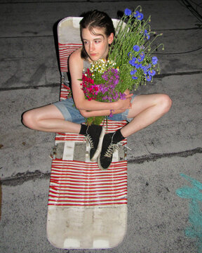 Young Person Holds Flower Bouquet on Roof at Night