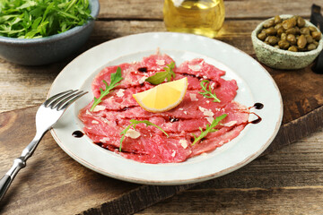 Delicious beef carpaccio served on wooden table, closeup