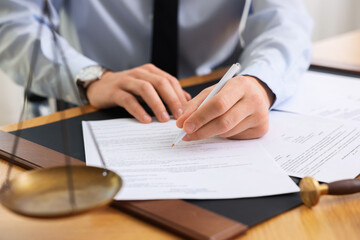 Notary signing document at table in office, closeup