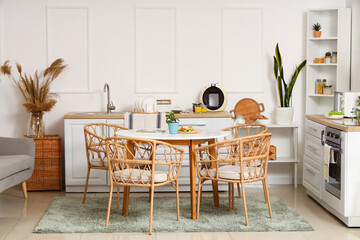 Interior of light kitchen with green plants, counters and dining table