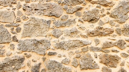 The walls of an old building made of piles of stones and wood stuck together with mud.