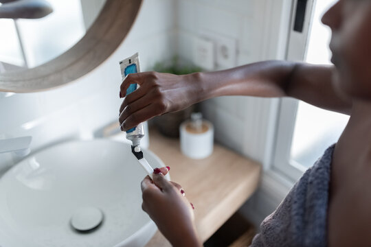 Woman applying toothpaste on brush
