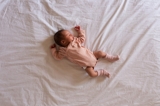 Carefree newborn sleeping on white bed