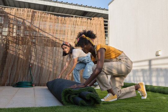Gardeners unrolling artificial turf