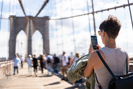 Tourist taking pictures on Brooklyn Bridge in Manhattan, New York City
