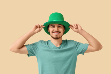 Happy young man in leprechaun's hat on beige background. St. Patrick's Day celebration