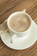 A warm cup of hot chocolate sits on a white plate, offering a cozy and inviting moment of comfort.

