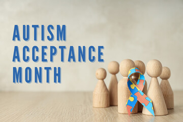 Autism Day, wooden figurines of men and ribbon with colorful puzzle on a light wooden background,...