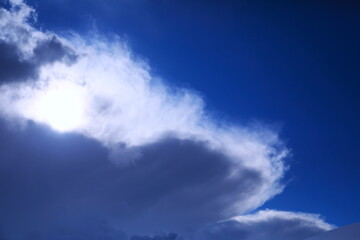 太陽光に浮かび上がる黒い雲と透き通るような白い雲