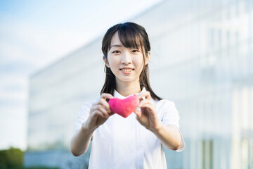ハート型の小物を持つ白衣の女性
