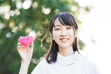 ハート型の小物を持つ白衣の女性