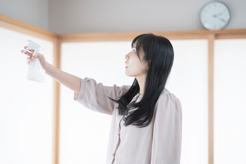 スプレーで部屋を消毒・殺菌する女性