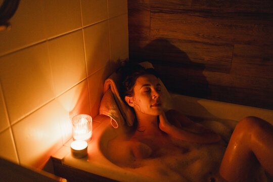Girl lying in the bathtub by candlelight
