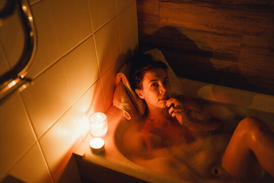Girl lying in the bathtub by candlelight