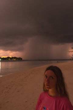 A woman on beach as storm approaches at dusk