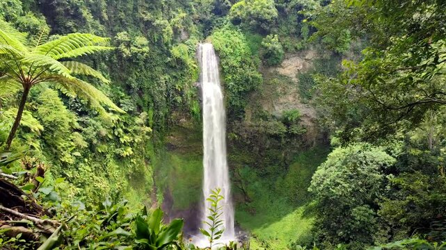 Curug Cimahi or Cimahi Waterfall, Indonesia, surrounded by lush green trees.