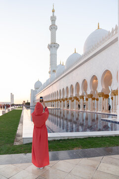 Woman wearing abaya taking photo at Grand Mosque using phone