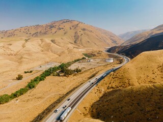 Aerial view of vehicles traveling on a Interstate 5, Grapevine, California,USA through a dry, hilly landscape. The scene captures transportation and the arid environment.