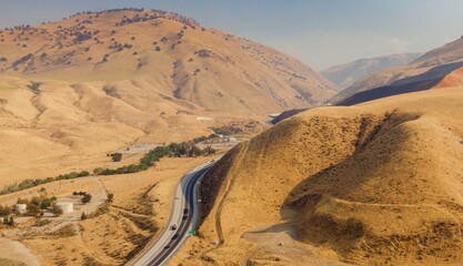 Cars travel along a highway through the arid, rolling hills of Grapevine, California, USA. The...