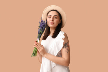 Beautiful young woman with bouquet of lavender flowers on beige background