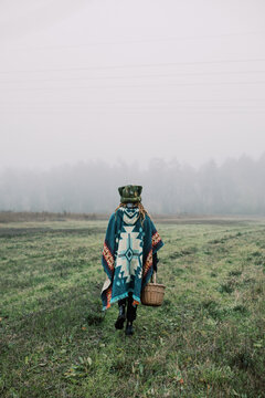 Woman in Poncho Walking Through Foggy Meadow