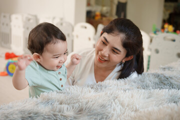 Cute Asian woman and little son playing educational toys together in living room. Mom and son play...