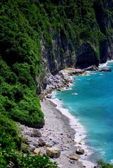 grey sand beaches over sheer tropical mountain cliffs, and bright blue ocean water