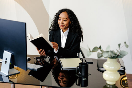 Professional woman looking at notebook at desk in office