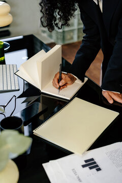 Crop anonymous businesswoman taking notes in notebook
